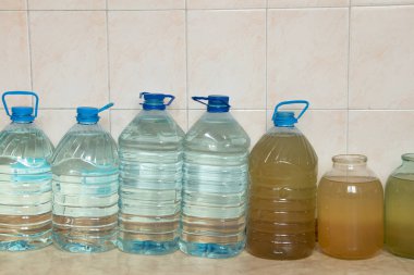 Ukrayna 'da bir evin zemininde su bulunan plastik şişeler, Ukrayna' daki roket saldırıları sırasında su kaynaklı su dolu şişeler, susuz ve ışıksız.