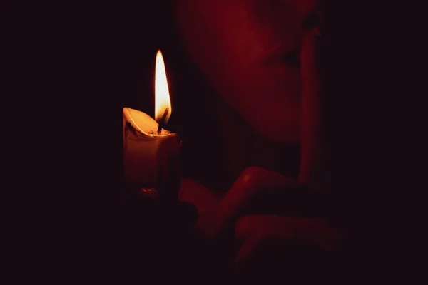 女孩在黑暗中握着一支蜡烛 露出了一个更安静的手指 一个秘密和一个祈祷者 — 图库照片