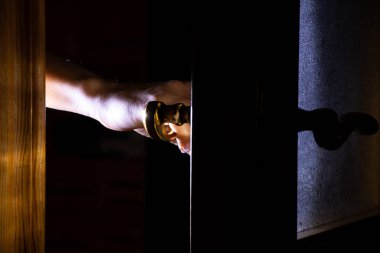 Karanlığın içinde kadın eli kapıyı açar, kapı tokmağı.