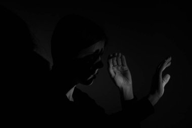 The girl covers her face with her hands from the bright light in the dark, the light shines in her face, the girl in the dark looks