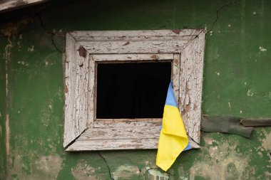 The flag of Ukraine hangs on the window of a destroyed residential building, the war and the shelling of Russian residential buildings in Ukraine