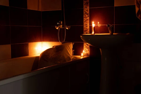 Bathroom as a shelter from rocket attacks in Ukraine by candlelight with a bed in the bathroom without light, war, sleeping in the bathroom