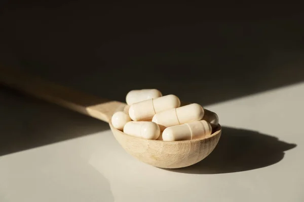 Pills in a wooden spoon on a table in the sun ,medicines and vitamins