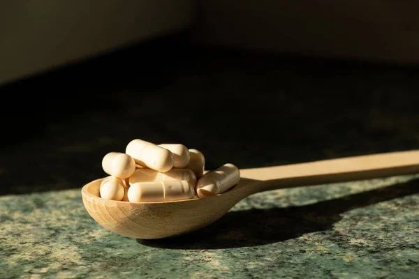Pills in a wooden spoon on a table in the sun ,medicines and vitamins