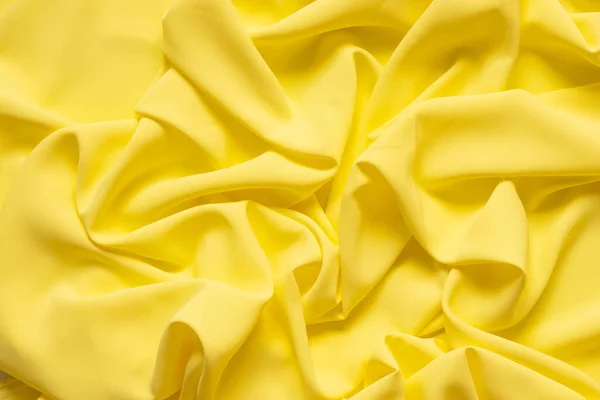 Yellow crumpled plain fabric as a background close up