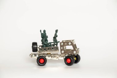 Plastik askerler ve küçük bir çocuk arabası beyaz arka planda eski bir demir inşaatçısından, bir savaş oyunu.