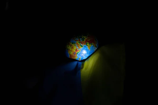 Рука Держит Флаг Украины Глобус Темноте Крупным Планом — стоковое фото
