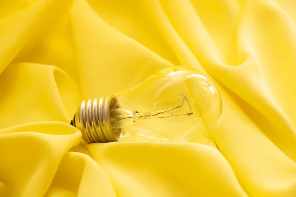 一盏白炽灯放在一块黄色的布上 — 图库照片
