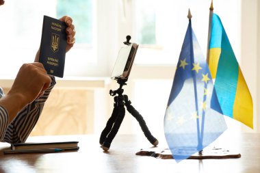Yabancı bir biyometrik Ukrayna pasaportu ve yanında Ukrayna ve Avrupa Birliği bayraklarını çevrimiçi video konferansı yoluyla göster