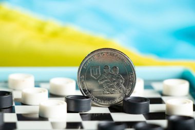 Ukrayna Silahlı Kuvvetleri 'nin 10 Hryvnia 2022 sayılı madeni parası dama ve arkasında Ukrayna bayrağı yatmaktadır.