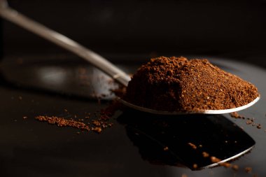 Siyah bir tabakta kavrulmuş kahveyle kaşık, arka plan için kahve.