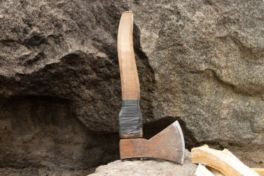 Yazın ormanda bir granit taşın üzerinde çalışan eski bir balta yakacak odun keserken, odun kesmek için bir alet, bir oduncu
