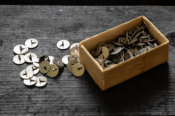 stock image Old round metal paper clips lie on a black wooden table next to it a paper box with paper clips, stationery