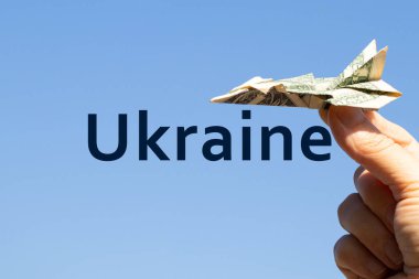Ukrayna üzerinde gökyüzündeki bir kızın elinde bir dolardan bir uçak ve arka planda Ukrayna metni, özgürlük ve yaşam.
