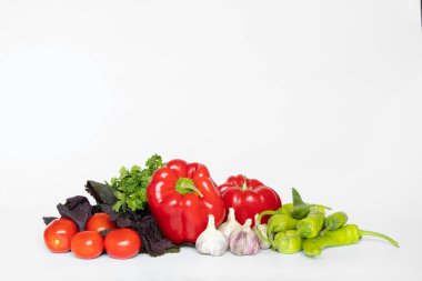 Biberler, sarımsak, domatesler, acı biberler beyaz arka planda yatar, adjika için malzemeler hazırdır, etsiz bir sebze seti.