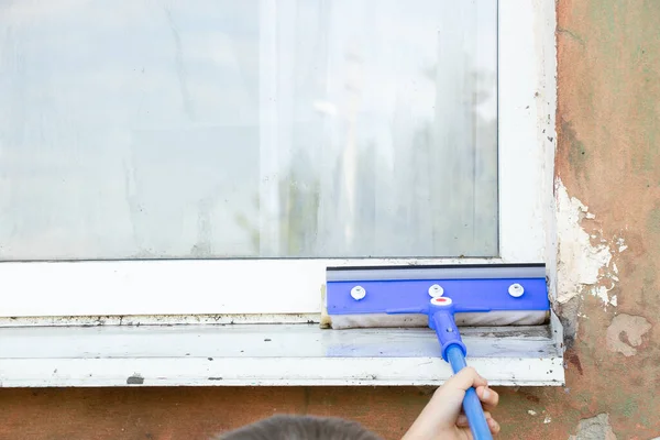 A child washes a dirty window with a mop from the street, wash windows