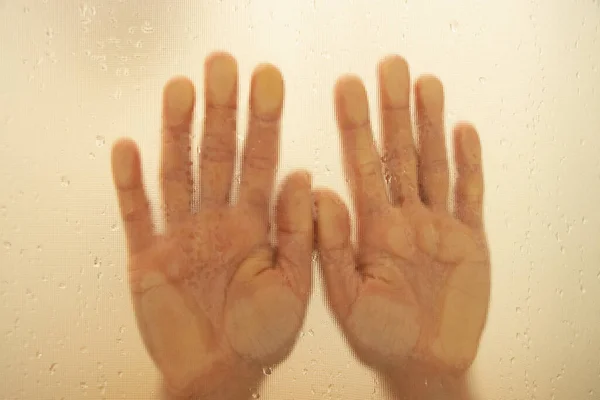 シャワーのクローズアップのウェットガラスの女性の手 シャワーに女の子が浴びる 彼女の手はガラスにあります — ストック写真