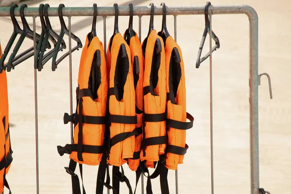 Life jackets hang on hangers on the street in the summer sun near the river
