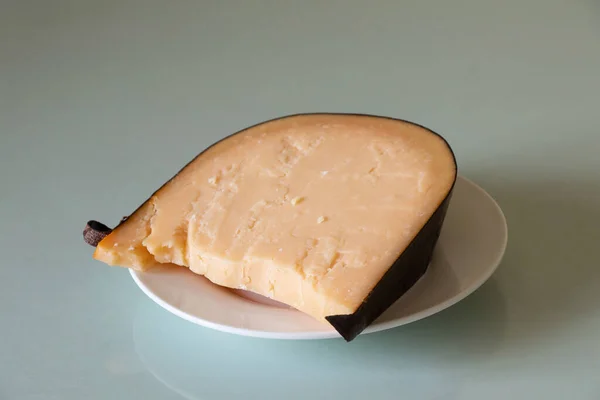 一块硬奶酪放在家中特写的玻璃桌上的盘子里 午餐用的奶酪 — 图库照片