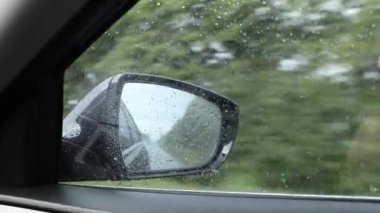 Araba penceresinin dışında yağmur, dikiz aynasından hız yapan bir arabanın görüntüsü, arabayla seyahat etmek, yağmurda araba sürmek, hava durumu.