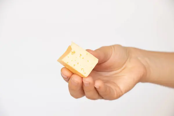 一个女孩拿着一块硬奶酪放在白色背景的特写上 — 图库照片