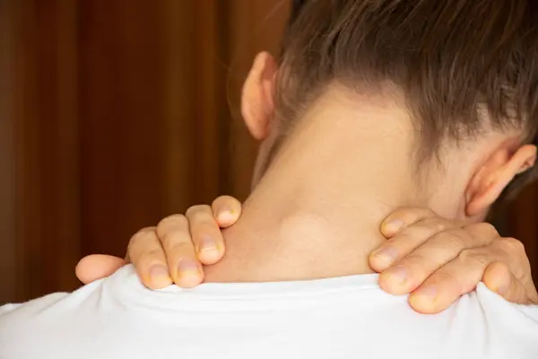 A girl holds her hands behind her neck at home, sore neck, acute pain in the neck