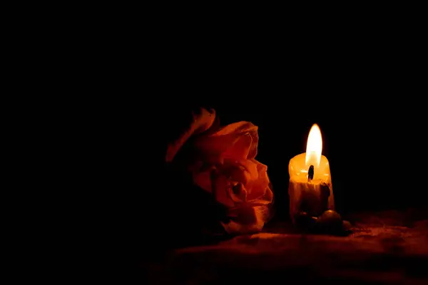 Candle flame and rose in the dark, mourning and sadness, grief for the dead