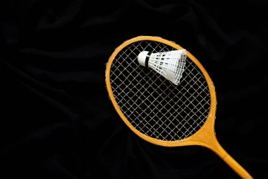 Old wooden racket and shuttlecock closeup on black fabric, sport and hobby