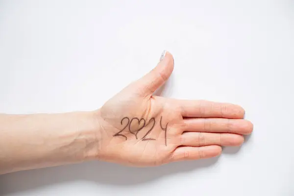 2024 and a heart in place of zero is written on a woman s hand which lies on a white background, help and support in the new year 2024, love