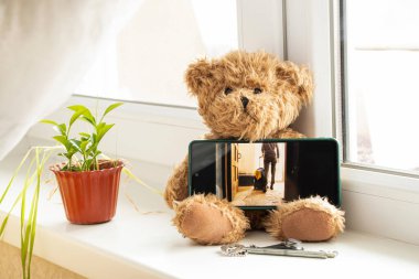 Ukraynalı bir kadın elinde bavul ve Ukrayna bayrağıyla girişten çıkıyor. Savaş sırasında Ukraynalı mülteciler. Evin penceresinde telefon ekranında fotoğrafı var.