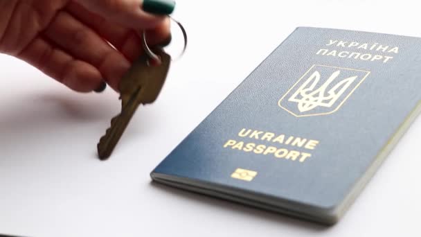 女性の手は テーブルの上にウクライナの外国のパスポートの隣に家のキーを置き ウクライナを離れ 家を出ます — ストック動画