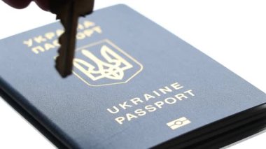 Kadının eli Ukrayna pasaportuna ev anahtarlarını koydu, ki bu pasaport aynada duruyor, Ukrayna 'yı, anahtarı ve pasaportu bıraktı.
