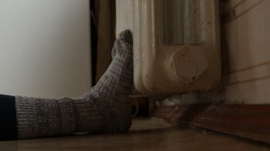 Apartmandaki dökme demir radyatörde çoraplar içinde ayaklar, ısıtma yok, kışın ısıtma yok.