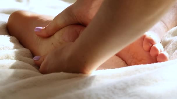 女の子はベッドのベッドルームで自宅の男性に足のマッサージを与える 足のマッサージ — ストック動画