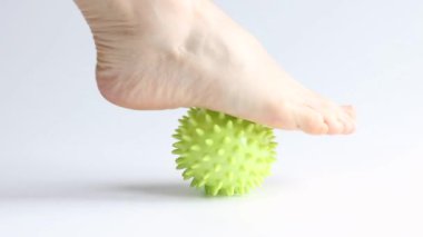 Bir kız ayaklarına beyaz arka planda sivri uçlu lastik bir topla masaj yapıyor, ayak masajı, spor ve sağlık.