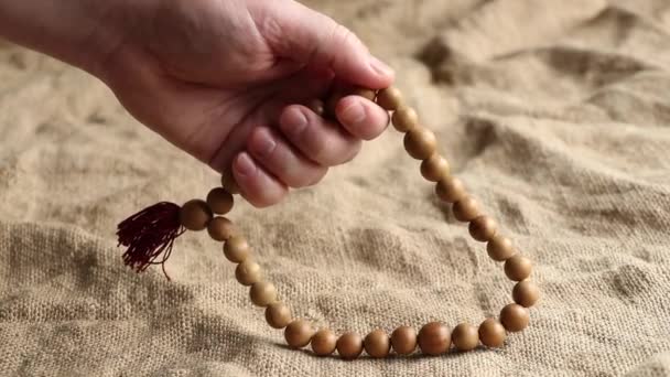 一个男人在他的手上摸着一个有着棕色背景的念珠 一个男性的手和一个念珠 一个祈祷和信仰的念珠 — 图库视频影像