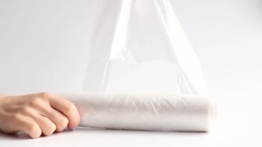 Kadın elleri, tek kullanımlık plastik poşetleri beyaz arka planda, tek kullanımlık poşetlere sarar.