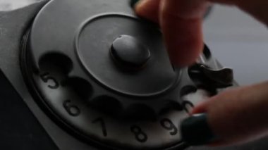 Bir kız eski bir siyah telefondan telefon numarası çeviriyor, numarayı çeviriyor.