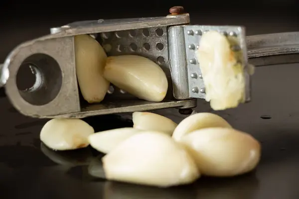 Crush garlic on a black plate, freshly squeezed garlic close-up