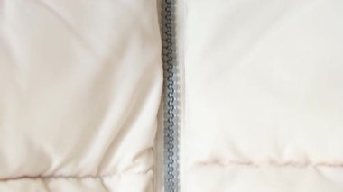 Beyaz kabarık kışlık ceket ve fermuar arka plan yakın plan, beyaz arka plan