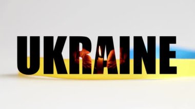 Ukrayna 'ya ve Ukrayna bayrağının düşen kurdelesinin arka planında mumlar olan ellere metin yaz