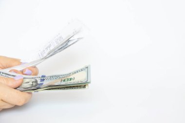 Bir kızın ellerinde bir marketten alınmış makbuzlar ve beyaz bir arka planda dolar, bir alışveriş bütçesi ve makbuzlar var.