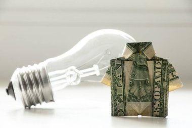 Dolar banknotlu gömlek ve beyaz arka planda parlak ampul, para ve elektrik, fiyat