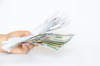 Bir kızın ellerinde bir marketten alınmış makbuzlar ve beyaz bir arka planda dolar, bir alışveriş bütçesi ve makbuzlar var.