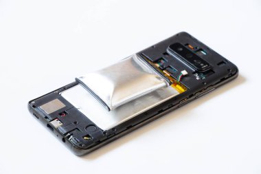 Aşırı ısınmadan dolayı şişmiş bir telefon ve parçalanmış bir telefon beyaz arka planda yatıyor, telefon pili şişmiş, telefon tamir ediliyor.