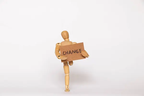 stock image One-legged wooden man holding paper card with text change on white background, life changes