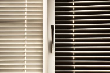 Gün boyunca apartmanın penceresinde beyaz panjurlar var.