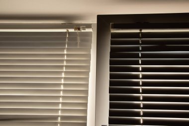 Gün boyunca apartmanın penceresinde beyaz panjurlar var.