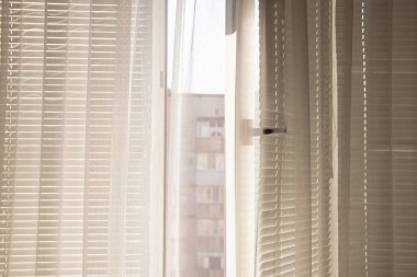 Ukrayna 'da komşu bir eve bakan beyaz perdeli ve perdeli bir pencere, apartman penceresinden manzaralı.