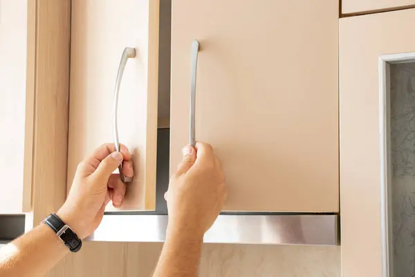 stock image Male hands opening beige kitchen cabinet in kitchen in apartment, kitchen furniture